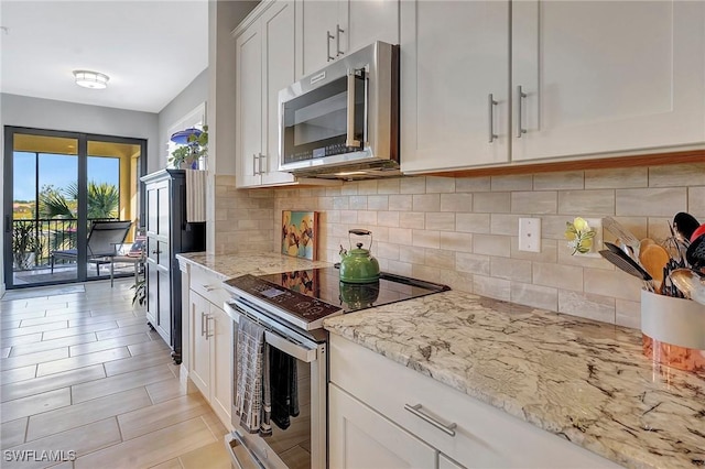 kitchen with backsplash, light stone countertops, white cabinetry, and stainless steel appliances