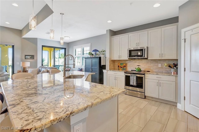 kitchen featuring stainless steel appliances, white cabinetry, a sink, and backsplash