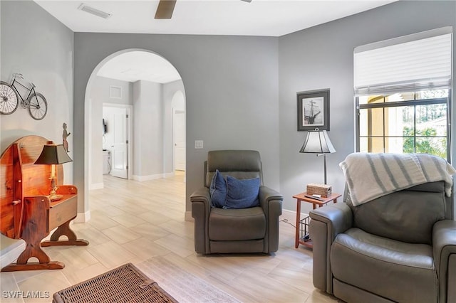 sitting room featuring visible vents, baseboards, a ceiling fan, and arched walkways