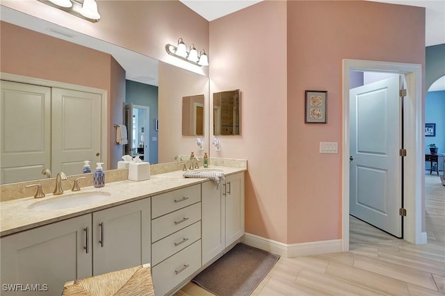 bathroom featuring double vanity, a sink, and baseboards