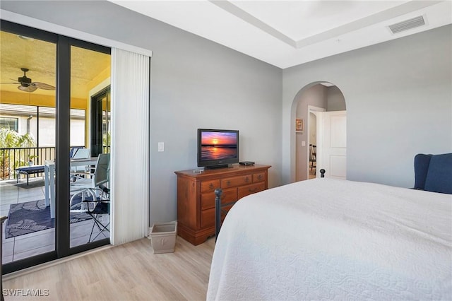 bedroom with visible vents, access to exterior, arched walkways, and wood finished floors