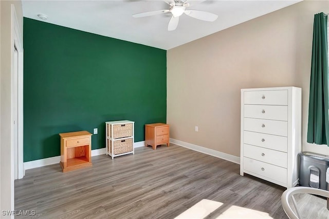 interior space featuring baseboards, a ceiling fan, and wood finished floors