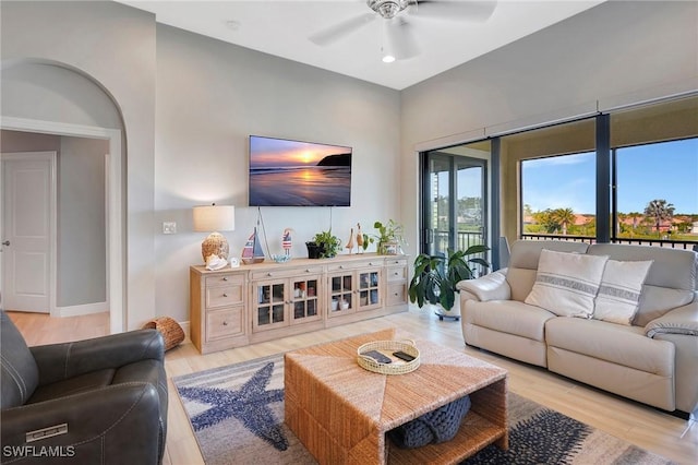 living room with light wood-style flooring, ceiling fan, and baseboards