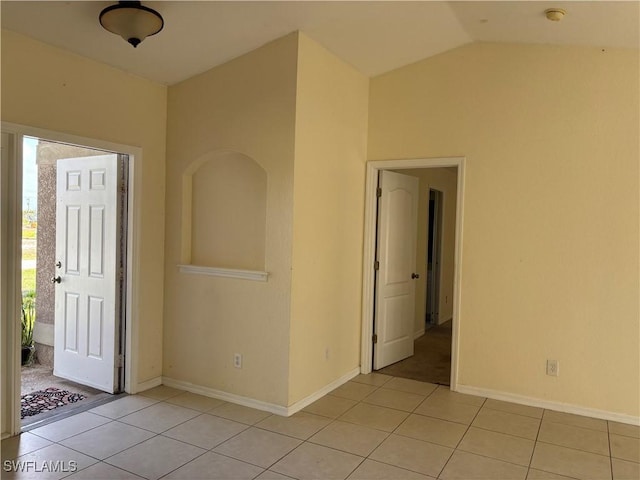 unfurnished room featuring lofted ceiling, light tile patterned flooring, and baseboards