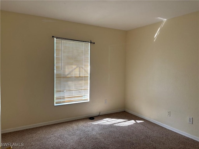 spare room featuring carpet and baseboards