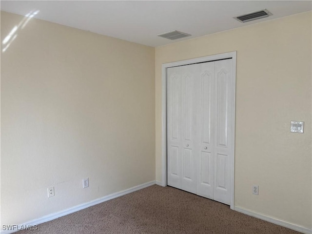 unfurnished bedroom with a closet, visible vents, baseboards, and carpet flooring