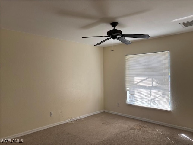 carpeted empty room with a ceiling fan, visible vents, and baseboards