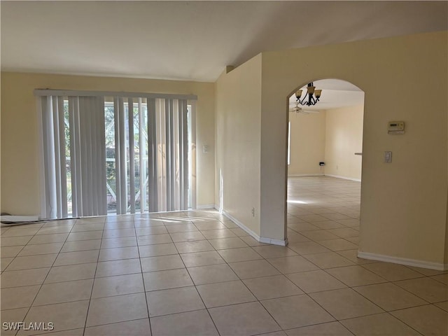 empty room with baseboards, arched walkways, vaulted ceiling, and light tile patterned flooring