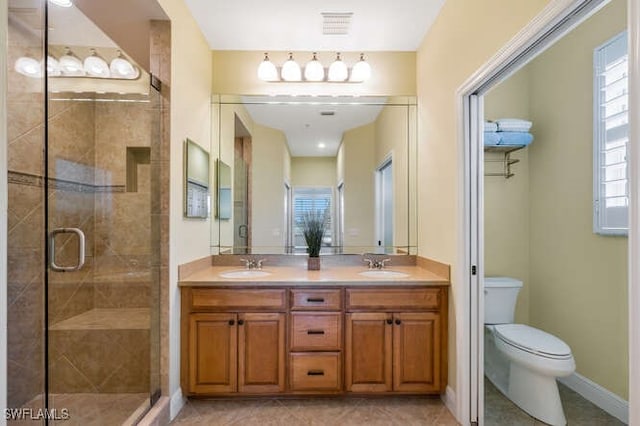 full bath with toilet, a stall shower, double vanity, and a sink