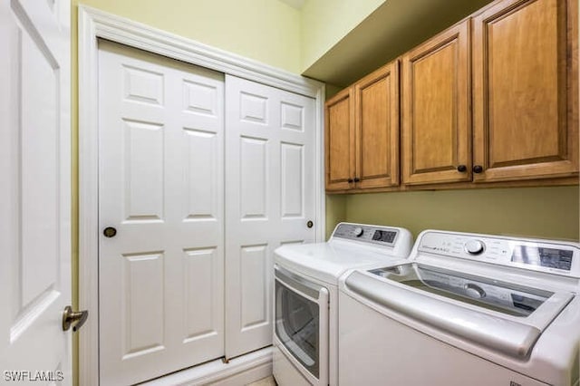 clothes washing area featuring cabinet space and washing machine and clothes dryer