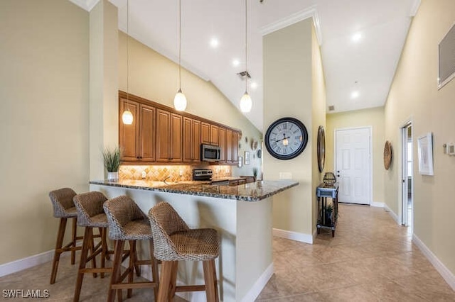 kitchen with stainless steel appliances, a breakfast bar area, dark stone countertops, and brown cabinets