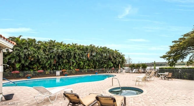 pool with a patio, a community hot tub, and fence