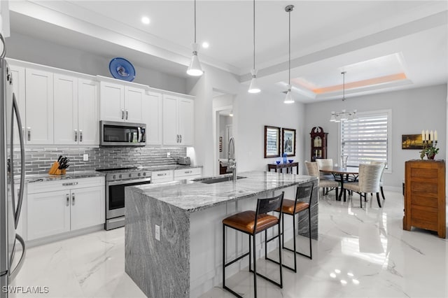 kitchen with a raised ceiling, light stone countertops, marble finish floor, stainless steel appliances, and a sink