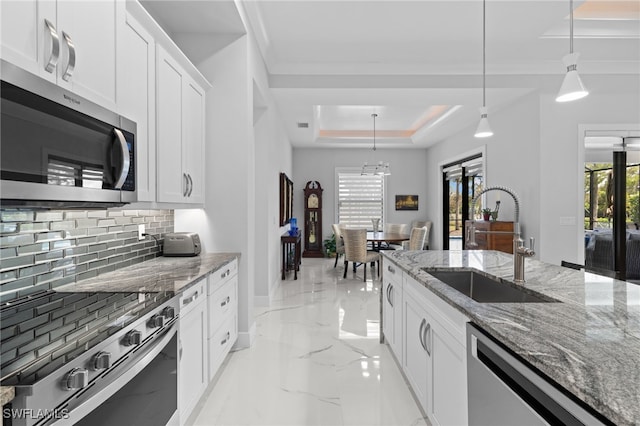 kitchen with stainless steel appliances, a sink, marble finish floor, backsplash, and a raised ceiling