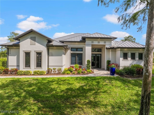 view of front facade featuring a front yard, a standing seam roof, metal roof, and stucco siding