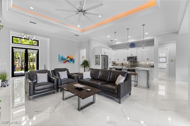 living room with a tray ceiling, french doors, marble finish floor, visible vents, and ornamental molding