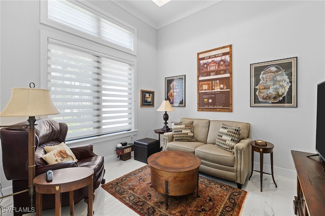 sitting room with crown molding, marble finish floor, plenty of natural light, and baseboards