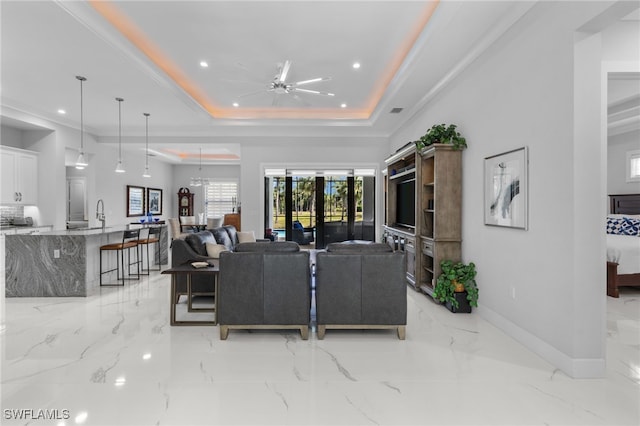 living room with a tray ceiling, marble finish floor, recessed lighting, ceiling fan, and baseboards