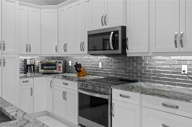 kitchen featuring stone countertops, white cabinets, marble finish floor, stainless steel appliances, and backsplash