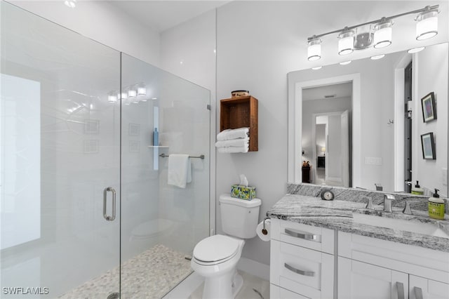 bathroom featuring vanity, a shower stall, and toilet