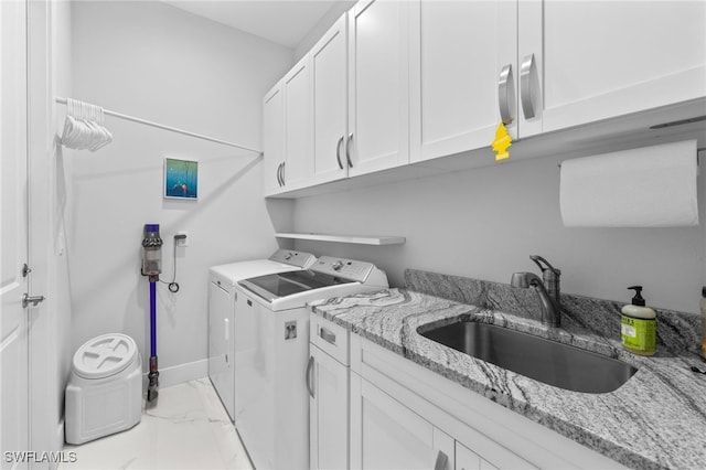 laundry area with a sink, baseboards, marble finish floor, cabinet space, and washing machine and clothes dryer