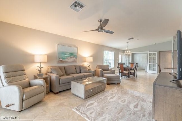 living room featuring light tile patterned floors, visible vents, vaulted ceiling, and ceiling fan with notable chandelier