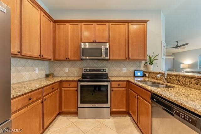 kitchen with light stone counters, light tile patterned floors, tasteful backsplash, appliances with stainless steel finishes, and a sink