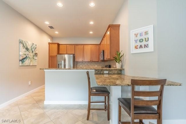 kitchen with visible vents, decorative backsplash, appliances with stainless steel finishes, dark stone counters, and a peninsula