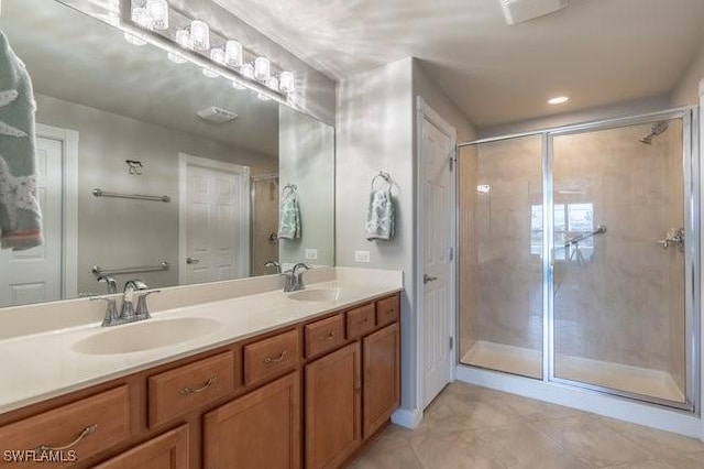 bathroom featuring double vanity, a stall shower, and a sink