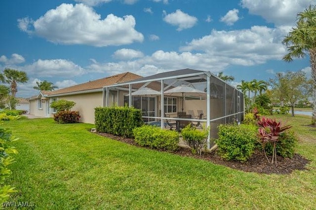 back of house with a yard and glass enclosure