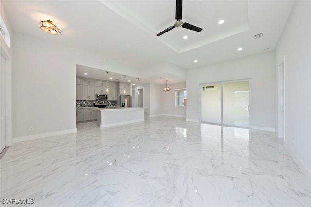 unfurnished living room featuring marble finish floor, visible vents, a raised ceiling, and recessed lighting