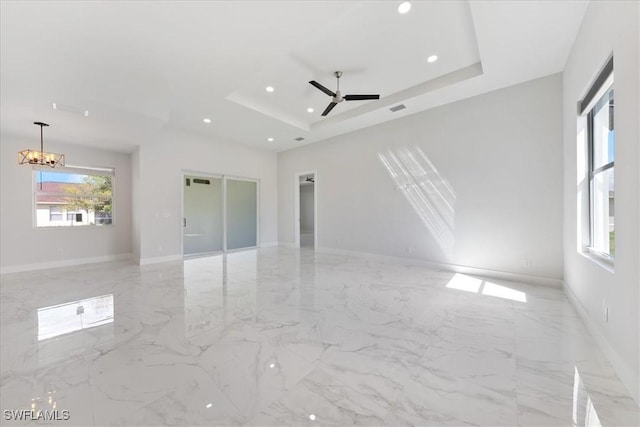 unfurnished room with marble finish floor, a tray ceiling, and recessed lighting