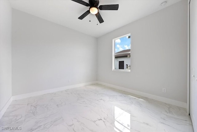 unfurnished room with marble finish floor, ceiling fan, and baseboards