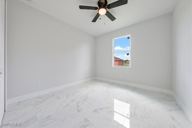 spare room with marble finish floor, ceiling fan, and baseboards