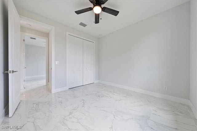 unfurnished bedroom featuring marble finish floor, a closet, visible vents, a ceiling fan, and baseboards