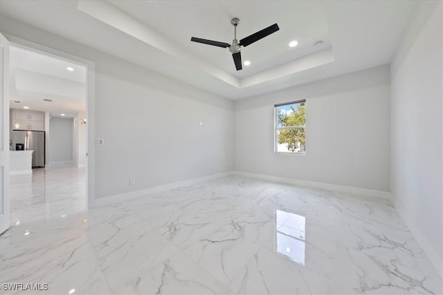 empty room with marble finish floor, recessed lighting, a raised ceiling, a ceiling fan, and baseboards