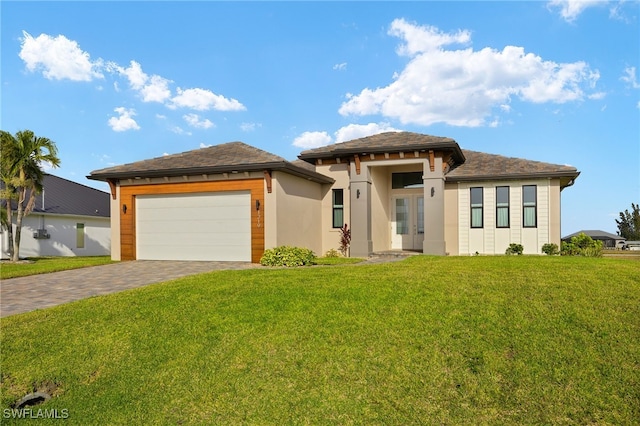 prairie-style house featuring an attached garage, decorative driveway, a front yard, and stucco siding