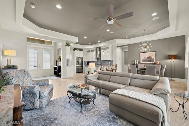 living area featuring light wood finished floors, french doors, a raised ceiling, and recessed lighting