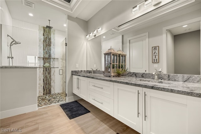 bathroom with double vanity, visible vents, a stall shower, a sink, and wood finished floors