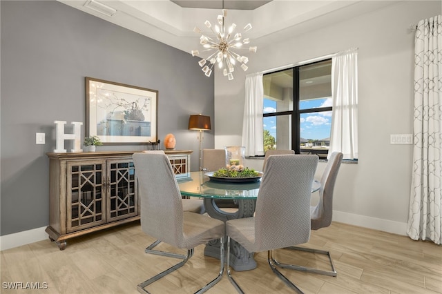 dining area with baseboards, wood finished floors, visible vents, and an inviting chandelier