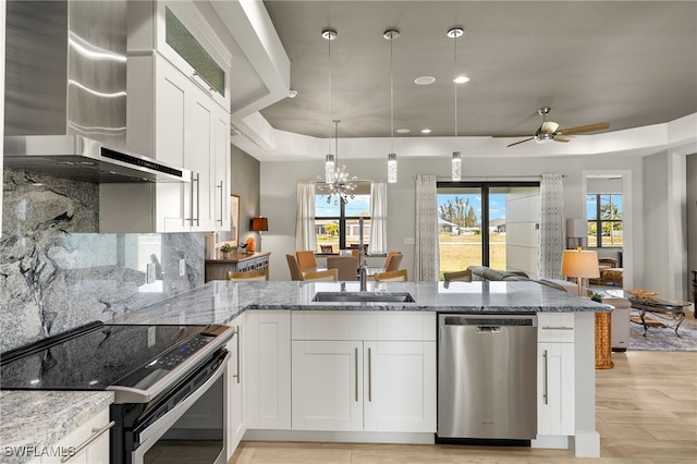 kitchen featuring light stone counters, wall chimney exhaust hood, dishwasher, and range with electric stovetop