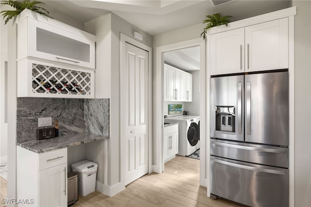 kitchen featuring stone countertops, white cabinetry, stainless steel fridge with ice dispenser, light wood finished floors, and tasteful backsplash