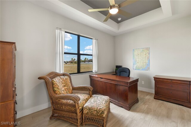 office with a ceiling fan, a raised ceiling, light wood-style flooring, and baseboards