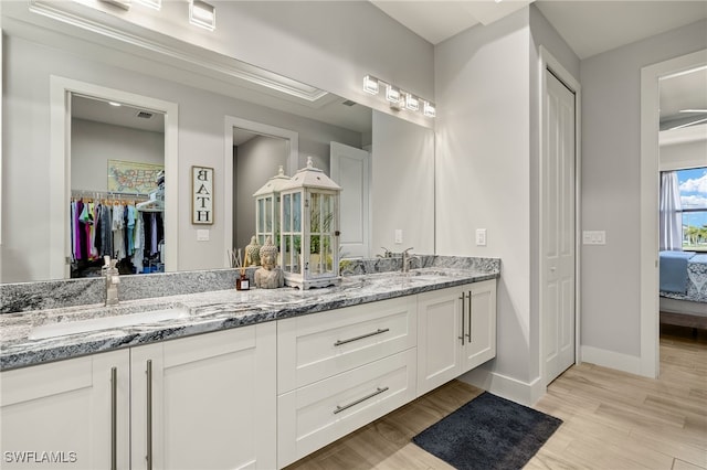 bathroom featuring double vanity, a sink, baseboards, and wood finished floors