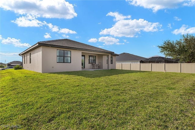 back of property featuring stucco siding, fence, a lawn, and a patio