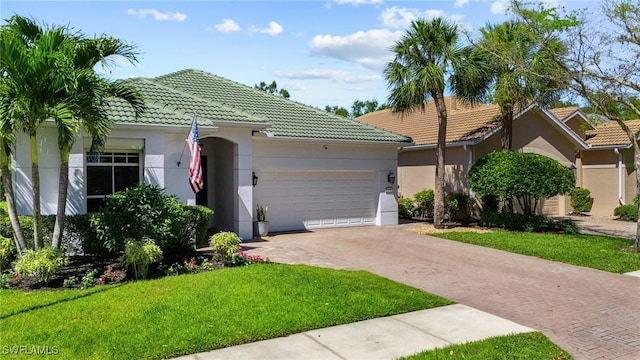 ranch-style house featuring a front yard, an attached garage, stucco siding, a tile roof, and decorative driveway