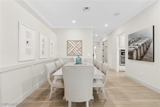 dining area with visible vents, crown molding, light wood-type flooring, recessed lighting, and a decorative wall