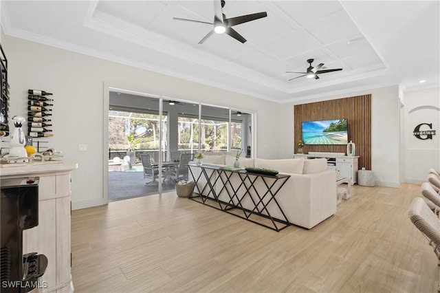 living room with light wood finished floors, ceiling fan, baseboards, and a tray ceiling