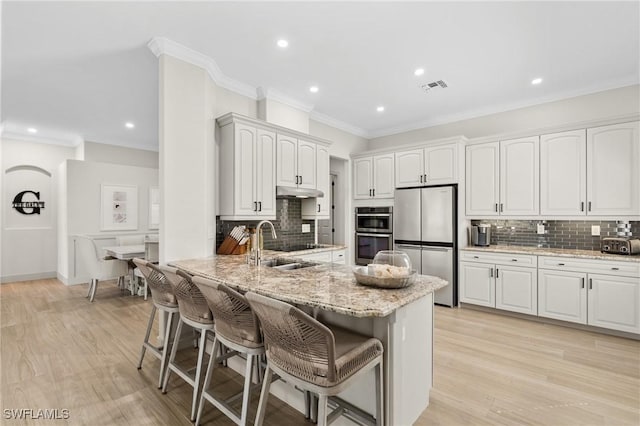 kitchen with a breakfast bar area, visible vents, a peninsula, a sink, and stainless steel appliances