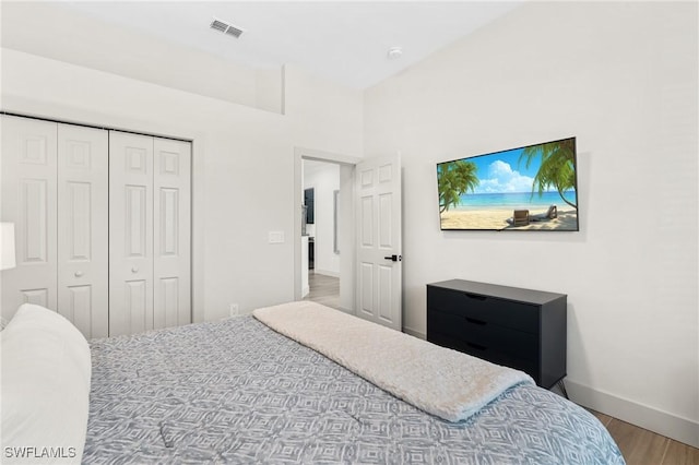 bedroom with wood finished floors, visible vents, a closet, and baseboards